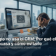 Empresario frustrado frente a un computador desconectado y una trituradora de billetes etiquetada como 'Inversión CRM'. Gráfico sobre el fracaso en la implementación de CRM.